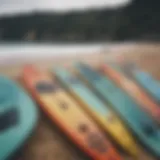 A variety of paddle boards displayed on a beach.