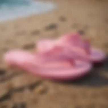 Stylish pink Sanuk flip flops on a beach